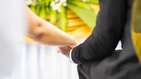 Les mains de deux mariés qui se tiennent, page d’un livre photo