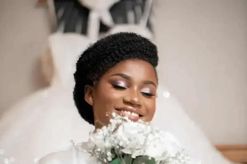 Bride in a robe holding her bouquet while getting ready