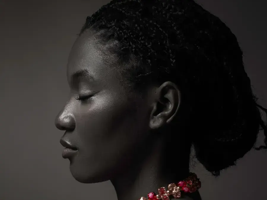 Profile portrait on a dark background, red necklace, taken at the L21STUDIOS studio