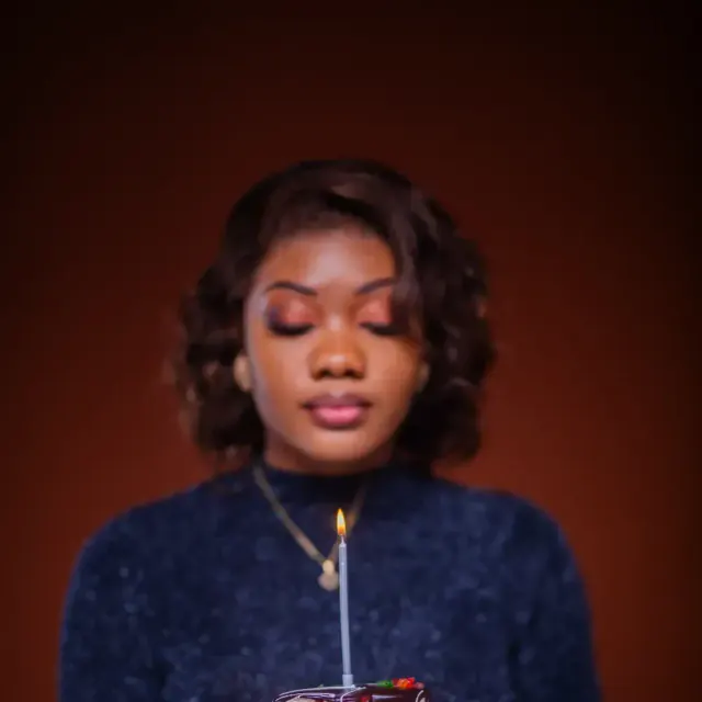 Portrait of a young woman holding a cake and its candle