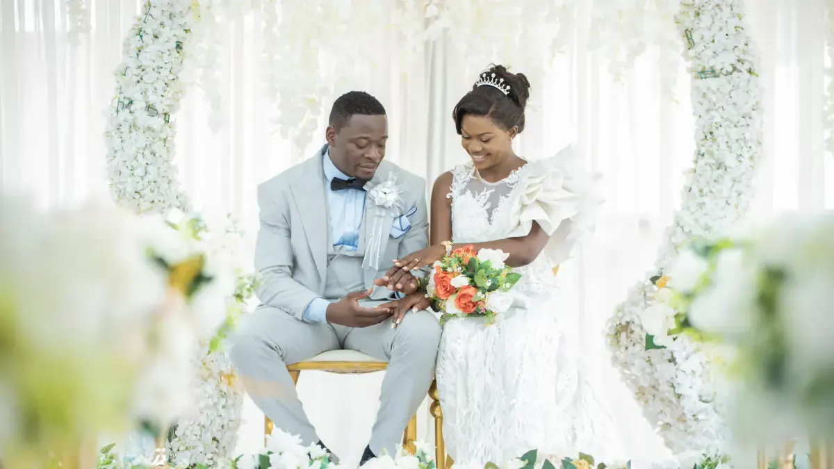 Bride and groom sitting under a floral arch, Yaoundé, photograph by L21STUDIOS