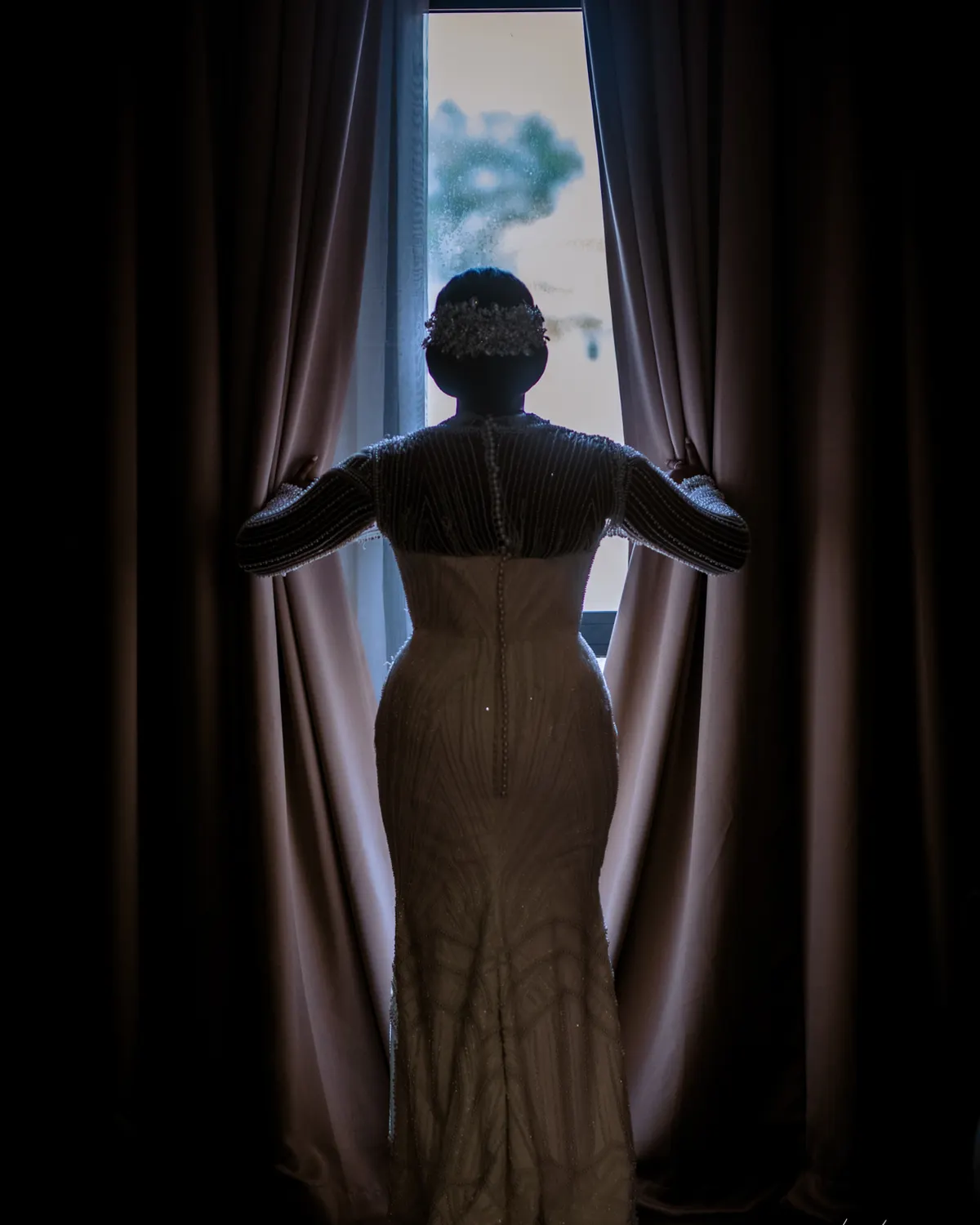 Bride seen from behind, opening the curtains against the light, photograph by L21STUDIOS