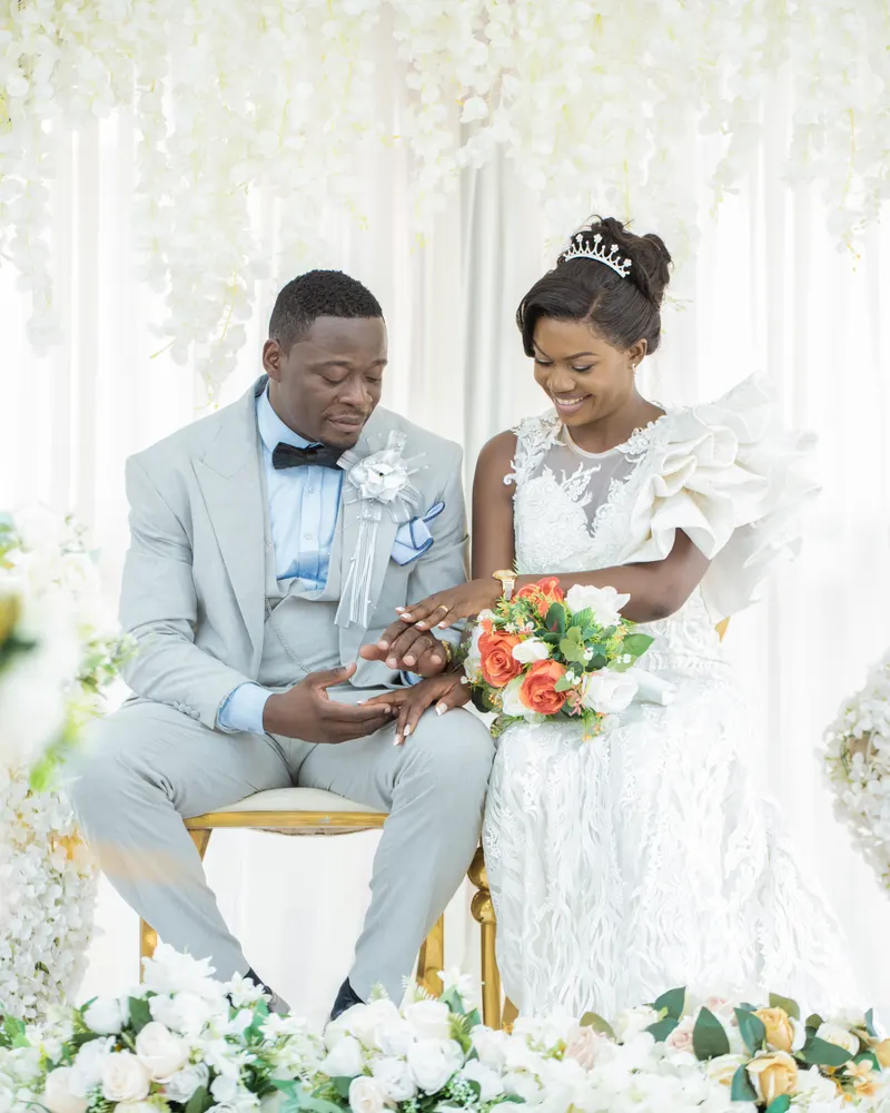 Bride and groom seated under a floral arch on their wedding day