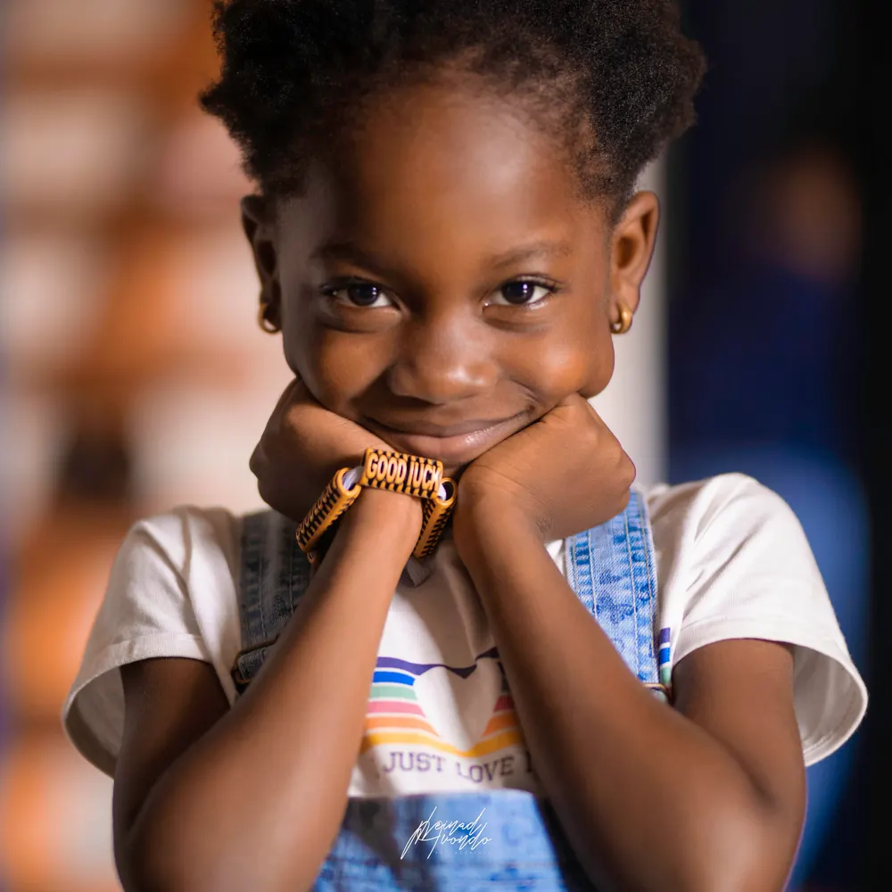Petite fille souriante, le menton dans les mains, photographie L21STUDIOS