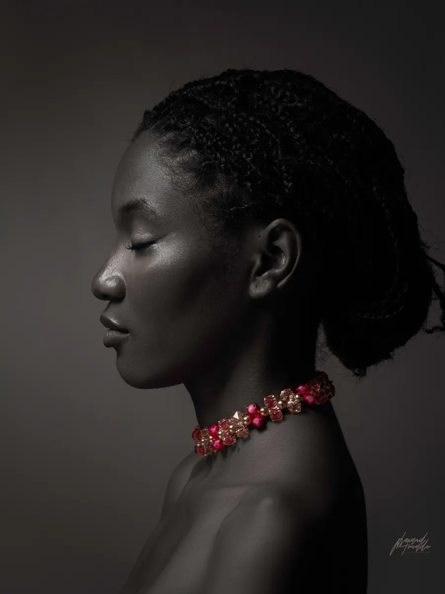 Portrait de profil en studio, collier rouge sur fond sombre, photographie L21STUDIOS