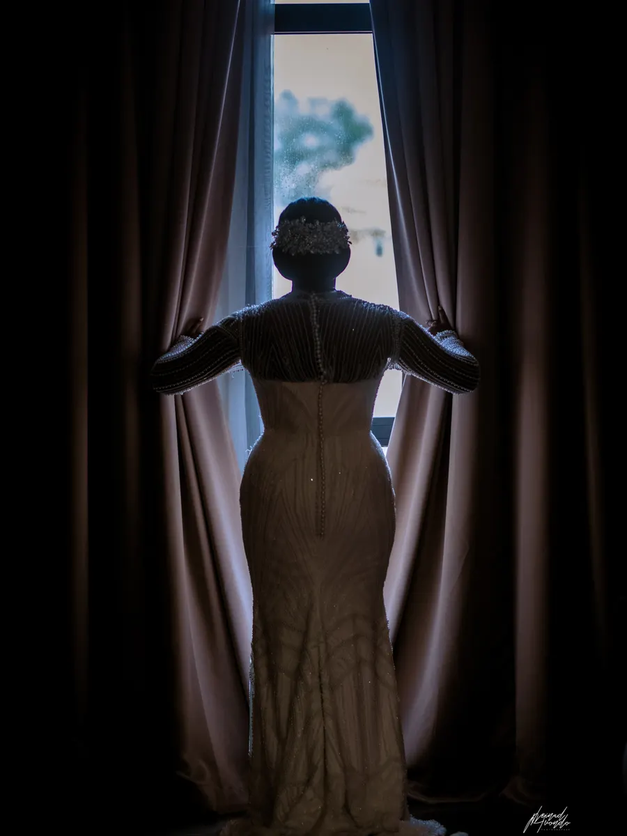Mariée de dos, ouvrant les rideaux en contre-jour, photographie L21STUDIOS